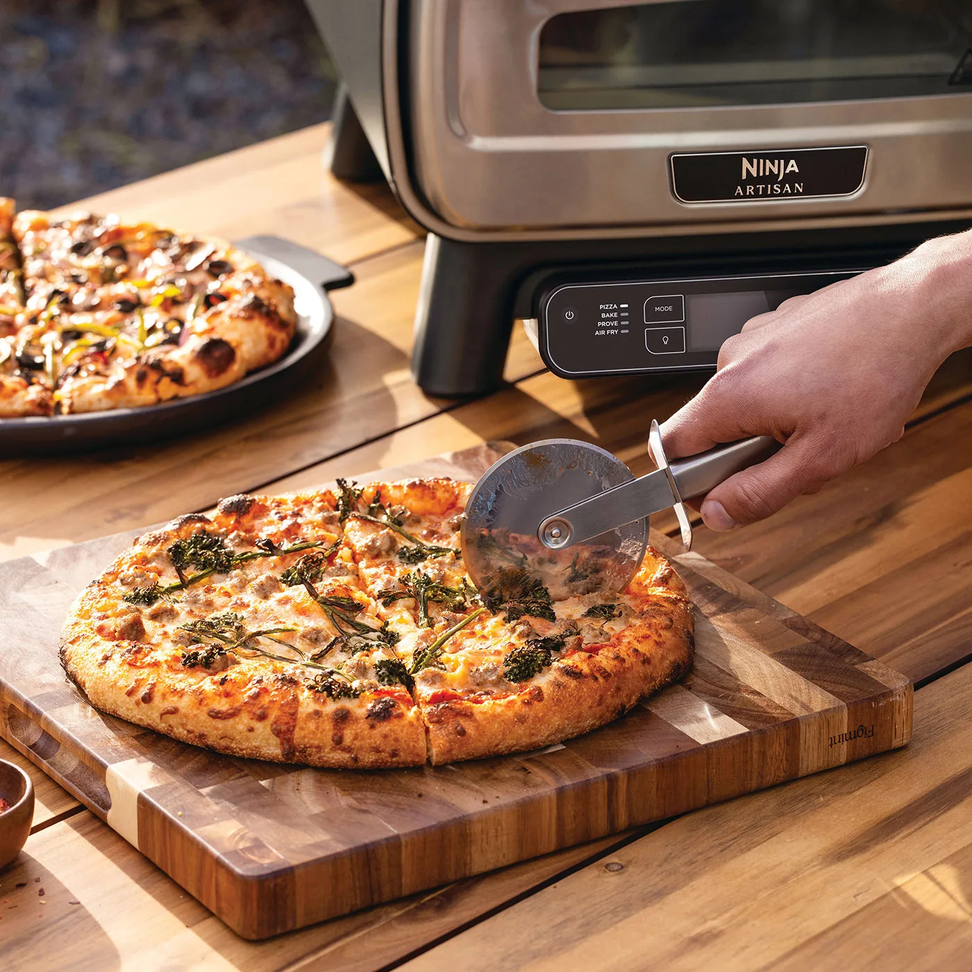 Ninja-MO201UK-InUse-BackYard-Table-SlicingPizza-Man